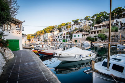 Boats moored at harbor against clear sky