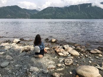 Rear view of woman sitting on rock