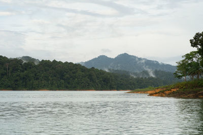 Scenic view of river by mountains against sky