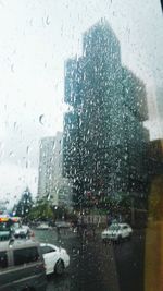 City seen through wet glass window during rainy season