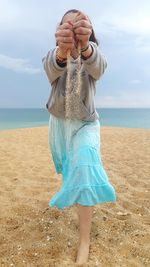 Midsection of woman at beach against sky