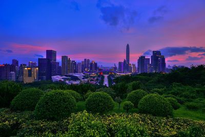 Trees and buildings against sky during sunset