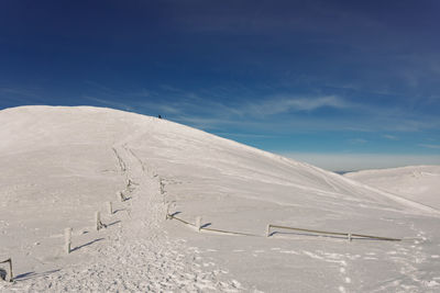 Scenic view of snow covered mountain against blue sky