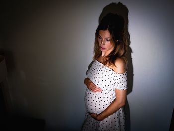 Pregnant woman standing against wall