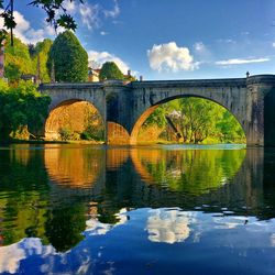 Arch bridge over river against sky