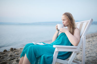 Rear view of woman sitting on beach