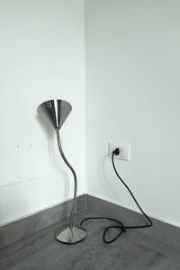 Electric lamp on table against white wall