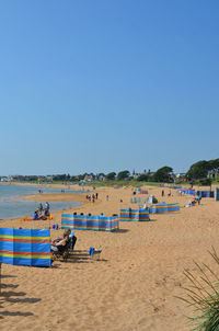 Panoramic view of people on beach against clear blue sky