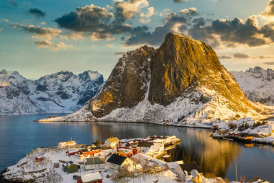 Scenic view of lake by snowcapped mountains against sky