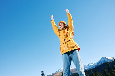 Low angle view of woman standing against clear blue sky