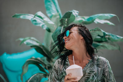 Portrait of a smiling young woman holding leaf outdoors