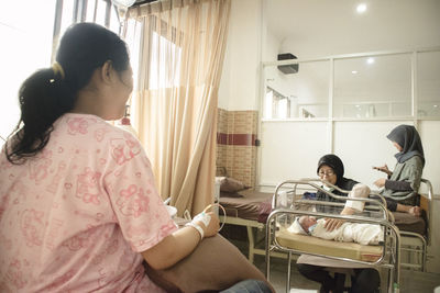 Rear view of women sitting on floor