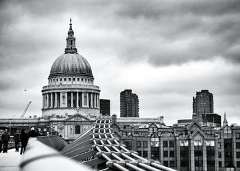 Millennium bridge with st paul cathedral against cloudy sky