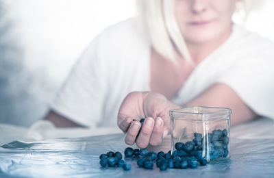 Midsection of woman holding blueberries on table