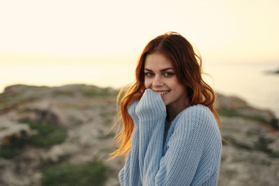 Portrait of smiling young woman standing against sky during sunset