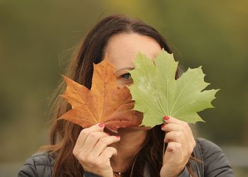 Close-up of woman holding autumn leaves