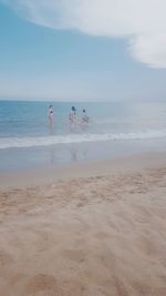 People enjoying at beach against sky