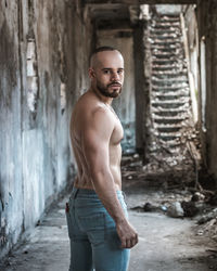 Portrait of shirtless man standing in abandoned building