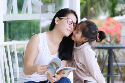 Mid adult woman with daughter sitting in back yard