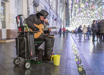 Mature man playing guitar on street during christmas