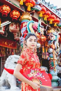 Portrait of teenager holding hand fan standing at temple