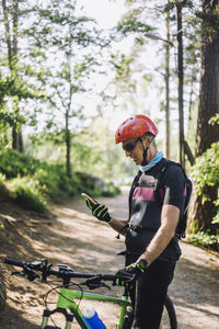 Man using smart phone while standing with cycle on footpath