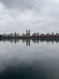 Reflection of building in lake against cloudy sky