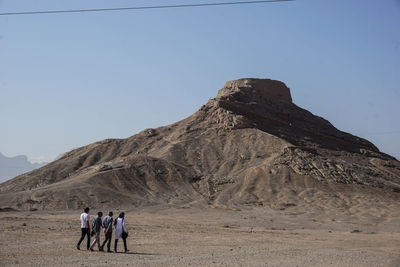 People on rock against clear sky