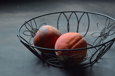 Peaches in black wire basket illuminated by window light