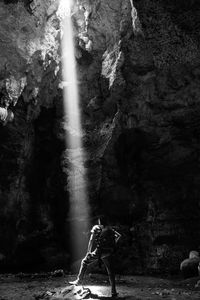 Rear view of man surfing on rock at waterfall