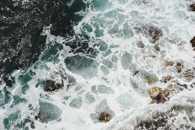 High angle view of sea waves splashing on rocks