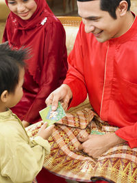 Father giving envelope to son hand at home