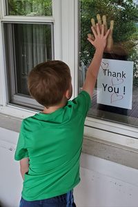 Rear view of boy standing by window