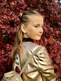 Portrait of girl standing against red flowering plants