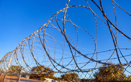 Low angle view of barbed wire against clear blue sky