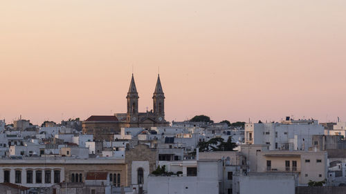 Buildings in city against sky during sunset