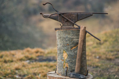 Bolt tongs and a hammer near a old rusty anvil outdoors with blurry background