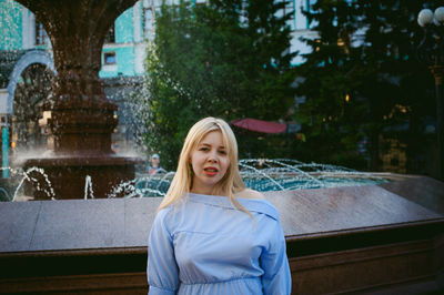 Portrait of woman standing against fountain