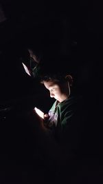 Boy using mobile phone in darkroom