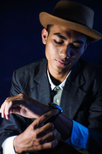 Close-up of man looking at wristwatch against black background
