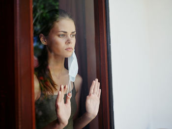 Portrait of beautiful young woman standing by window