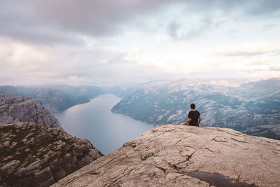 Man sitting in rock at edge of cliff at preikestolen, norway