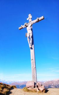 Cross sculpture against blue sky