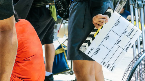 Midsection of man standing with film slate by people