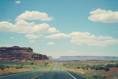 Road leading towards landscape against sky