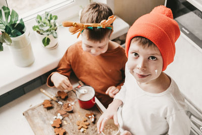 Children drink cocoa with marshmallows and christmas gingerbread man on a wooden background. 