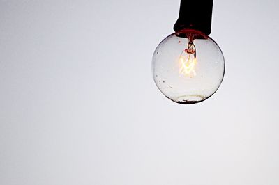 Close-up of light bulb hanging over white background