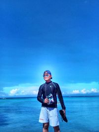 Full length of man standing in sea against blue sky