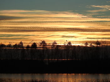 Scenic view of silhouette field against sky at sunset