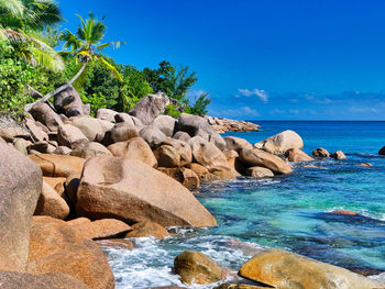 Rocks by sea against blue sky